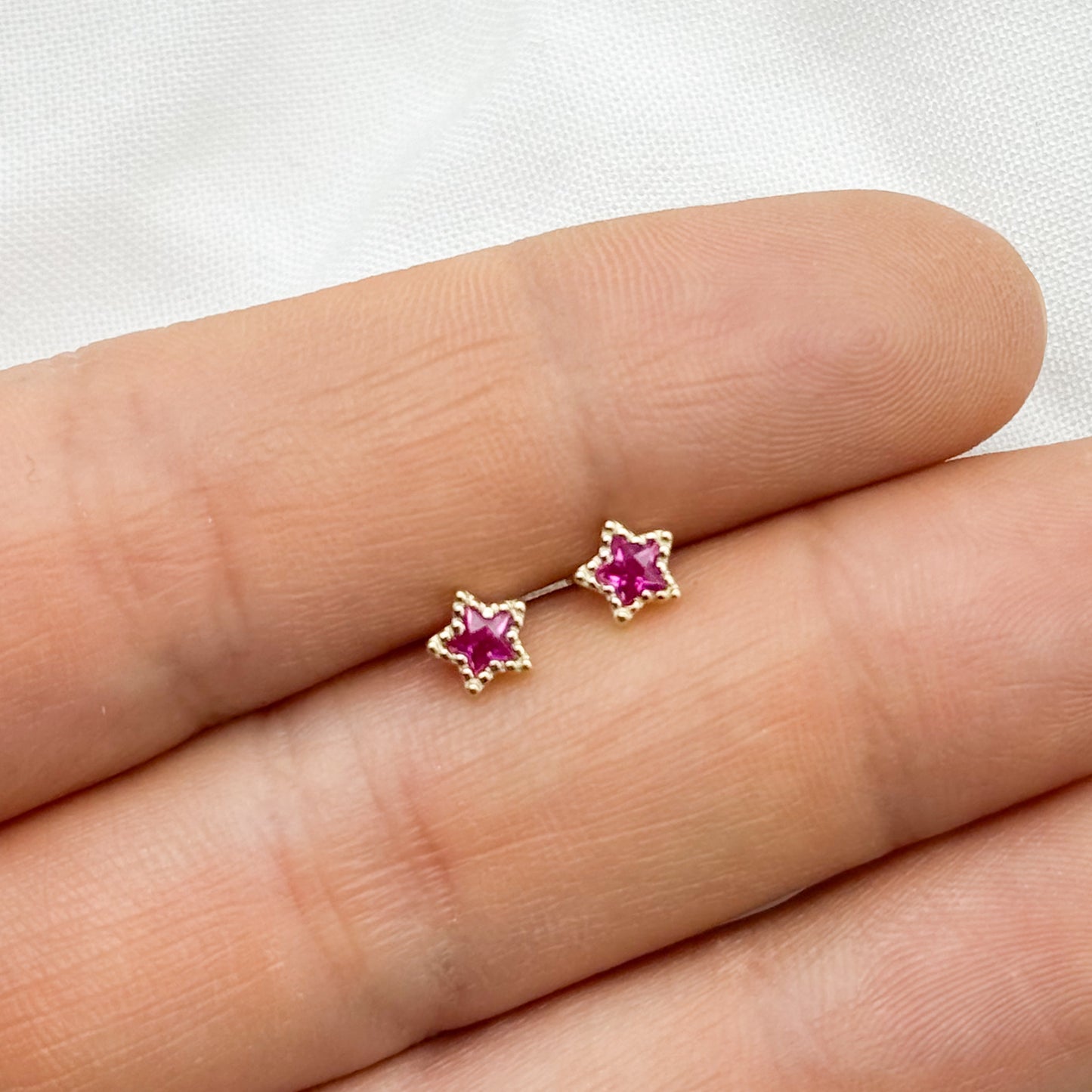 Aros pegados estrella fucsia cierre pelotita bañado en oro